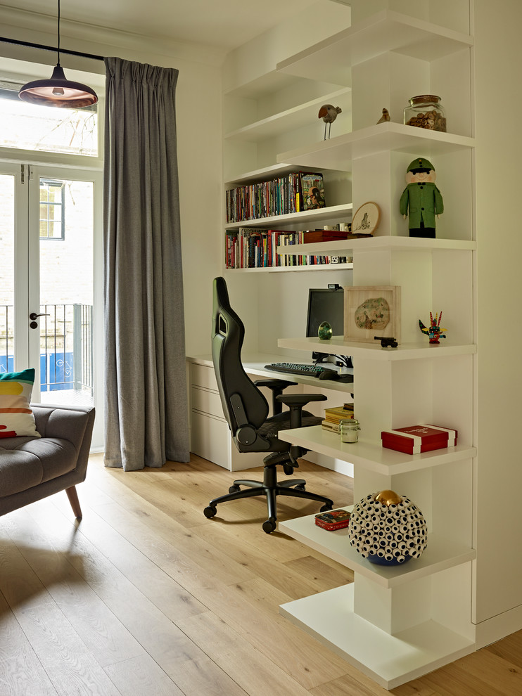 Mid-sized contemporary study room in London with white walls, light hardwood floors, a freestanding desk and beige floor.
