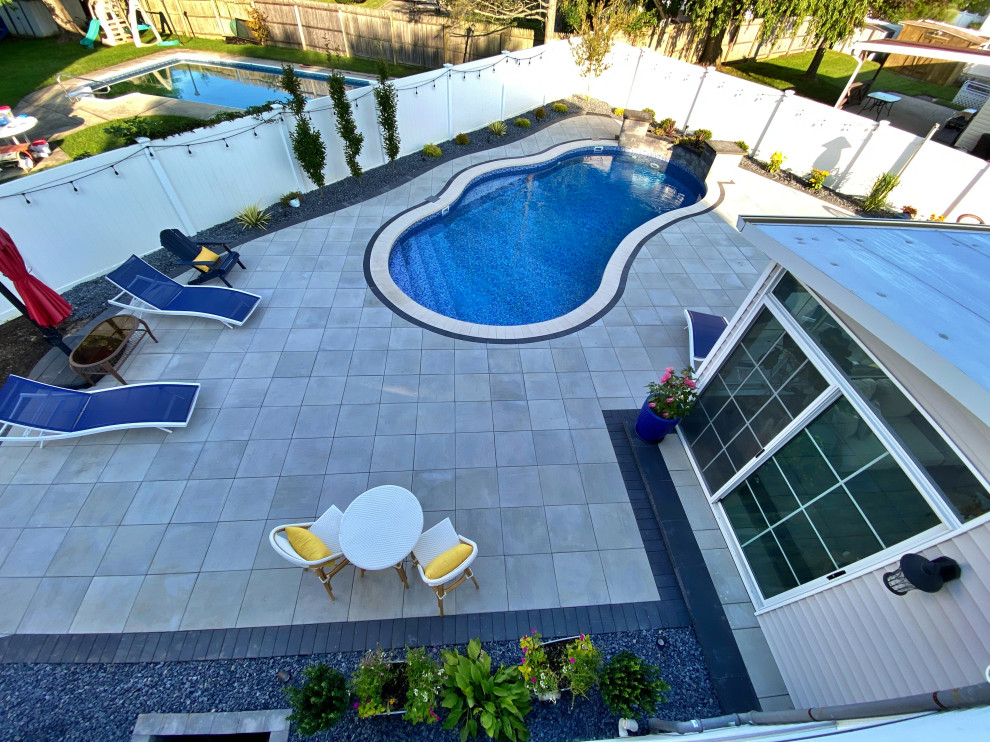 Inspiration for a large modern backyard kidney-shaped lap pool in New York with a water feature and concrete pavers.