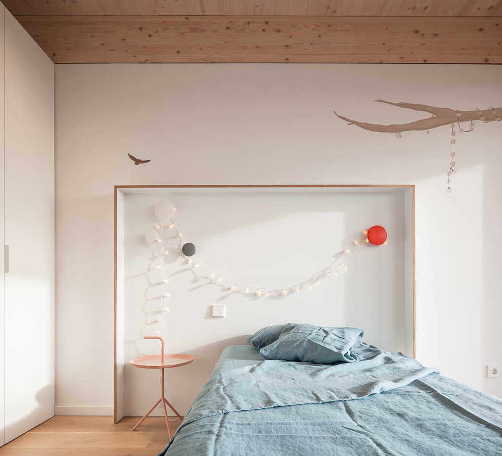 Contemporary gender-neutral kids' bedroom in Other with white walls, light hardwood floors and beige floor.
