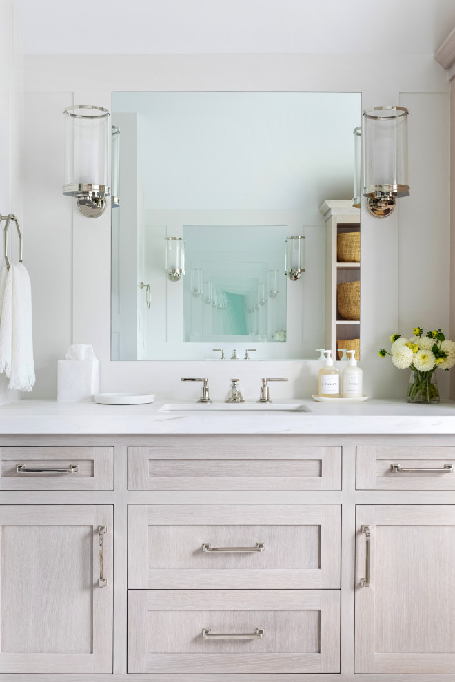 This is an example of an expansive traditional master bathroom in New York with recessed-panel cabinets, light wood cabinets, a claw-foot tub, an alcove shower, a one-piece toilet, white tile, white walls, an integrated sink, marble benchtops, white floor, a hinged shower door and white benchtops.