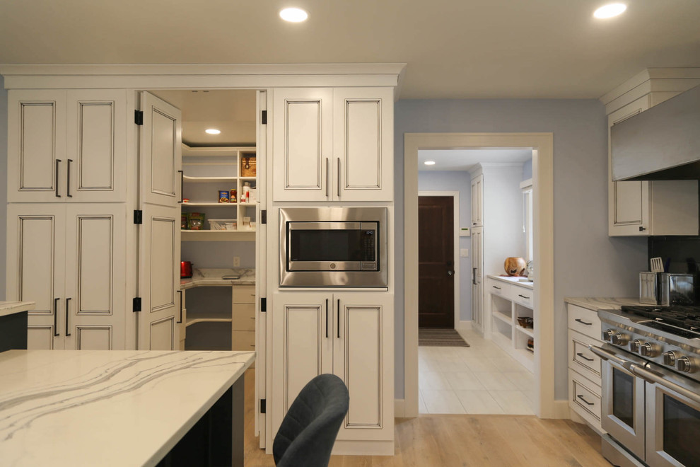 Eat-in kitchen - mid-sized transitional u-shaped light wood floor and beige floor eat-in kitchen idea with an undermount sink, recessed-panel cabinets, white cabinets, quartzite countertops, black backsplash, porcelain backsplash, stainless steel appliances, an island and white countertops