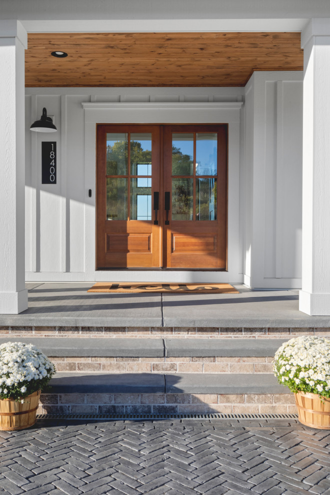 Große Landhaus Haustür mit weißer Wandfarbe, Backsteinboden, Doppeltür, hellbrauner Holzhaustür, grauem Boden und Holzdecke in Milwaukee