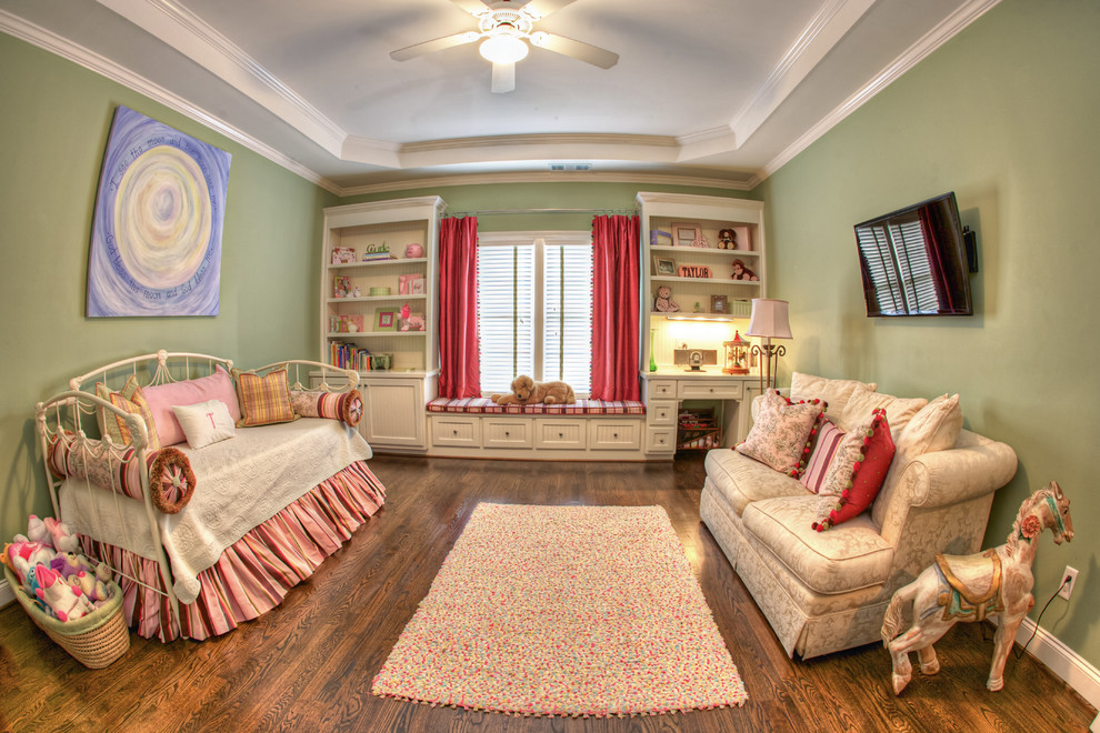 This is an example of a mid-sized traditional nursery for girls in Atlanta with green walls and medium hardwood floors.