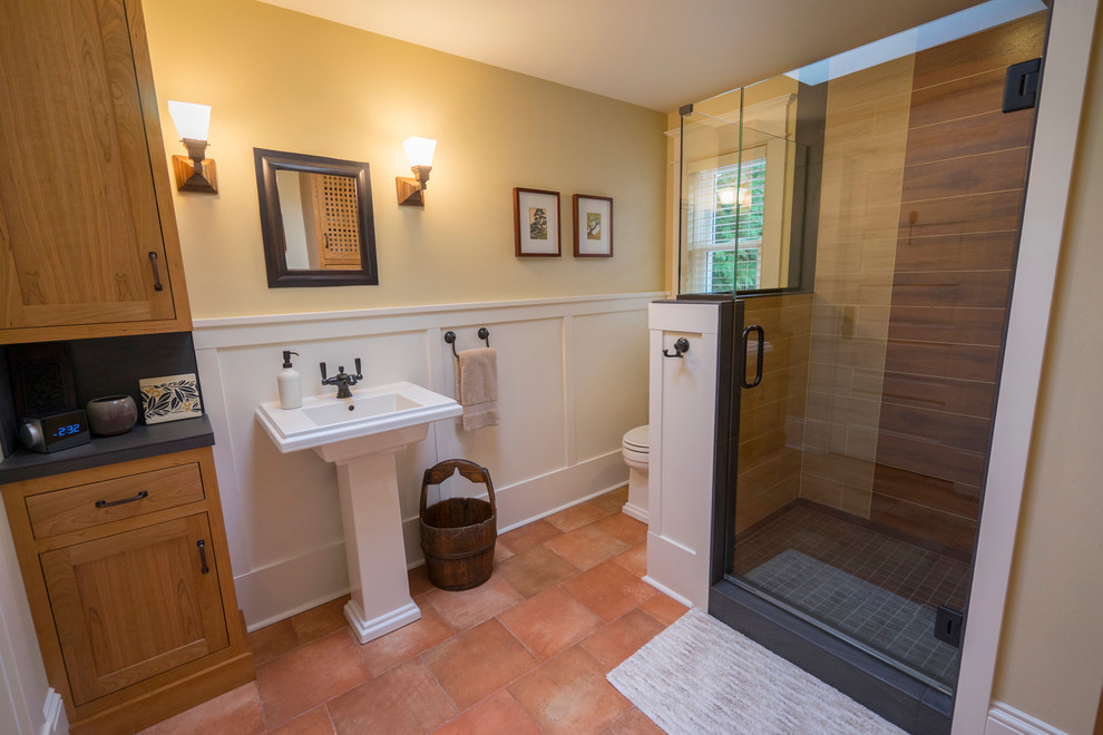 This is an example of a mid-sized arts and crafts 3/4 bathroom in Seattle with shaker cabinets, medium wood cabinets, a two-piece toilet, black tile, porcelain tile, yellow walls, porcelain floors, a pedestal sink and a corner shower.