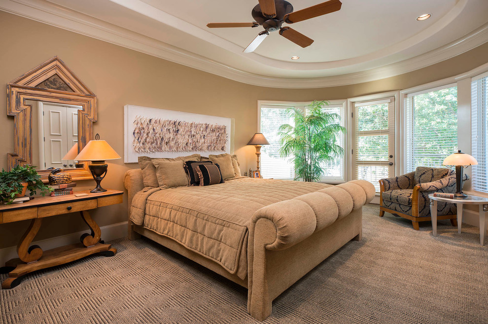 This is an example of an expansive tropical master bedroom in Dallas with beige walls and carpet.