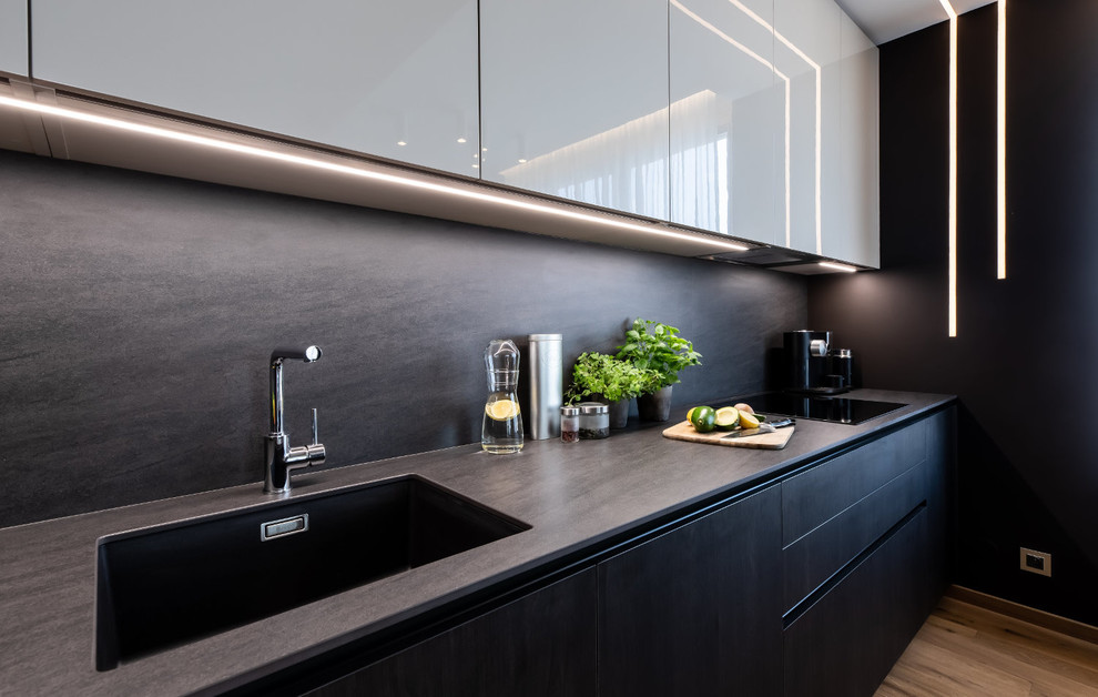 Inspiration for a mid-sized contemporary l-shaped eat-in kitchen in Other with an integrated sink, flat-panel cabinets, dark wood cabinets, limestone benchtops, stainless steel appliances, light hardwood floors and no island.