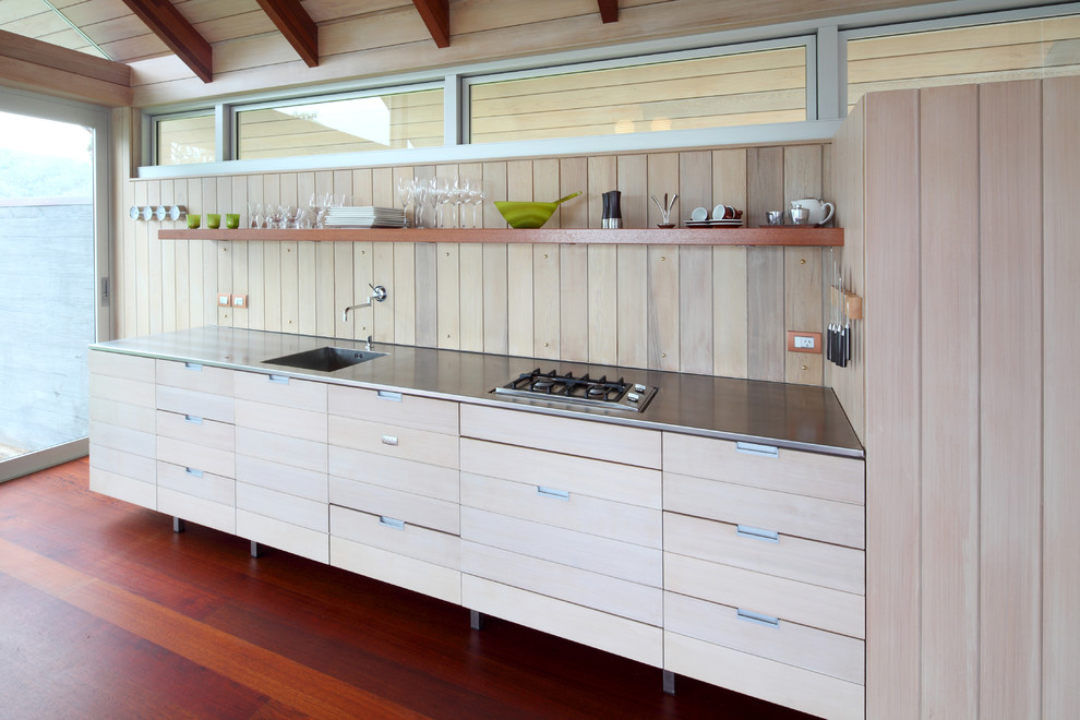 This is an example of a small contemporary single-wall kitchen in Other with light wood cabinets, stainless steel benchtops, panelled appliances, dark hardwood floors and no island.