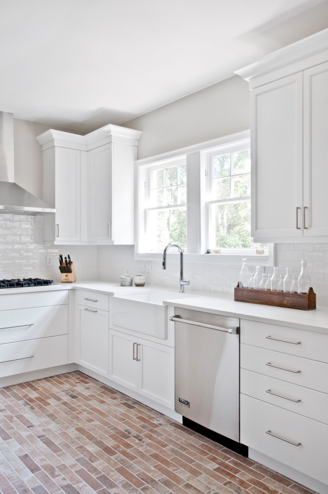 This is an example of a small transitional galley separate kitchen in Nashville with a farmhouse sink, recessed-panel cabinets, white cabinets, quartz benchtops, white splashback, ceramic splashback, stainless steel appliances, porcelain floors, no island, multi-coloured floor and white benchtop.
