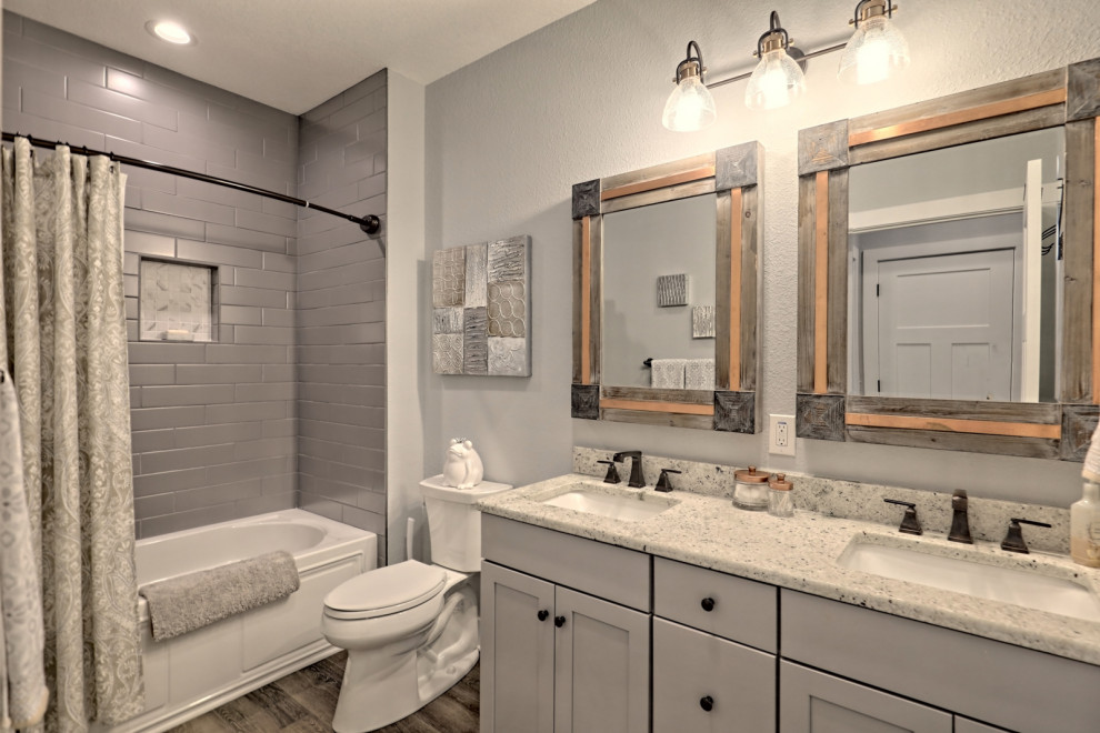 Inredning av ett amerikanskt stort vit vitt badrum, med skåp i shakerstil, grå skåp, ett badkar i en alkov, en dusch/badkar-kombination, en toalettstol med separat cisternkåpa, grå väggar, vinylgolv, ett undermonterad handfat, granitbänkskiva, grått golv och dusch med duschdraperi