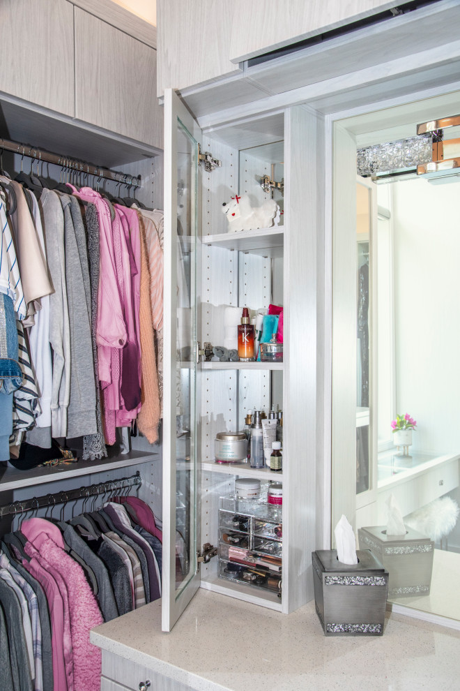 This is an example of a mid-sized transitional women's walk-in wardrobe in Chicago with flat-panel cabinets, light wood cabinets, medium hardwood floors, brown floor and vaulted.