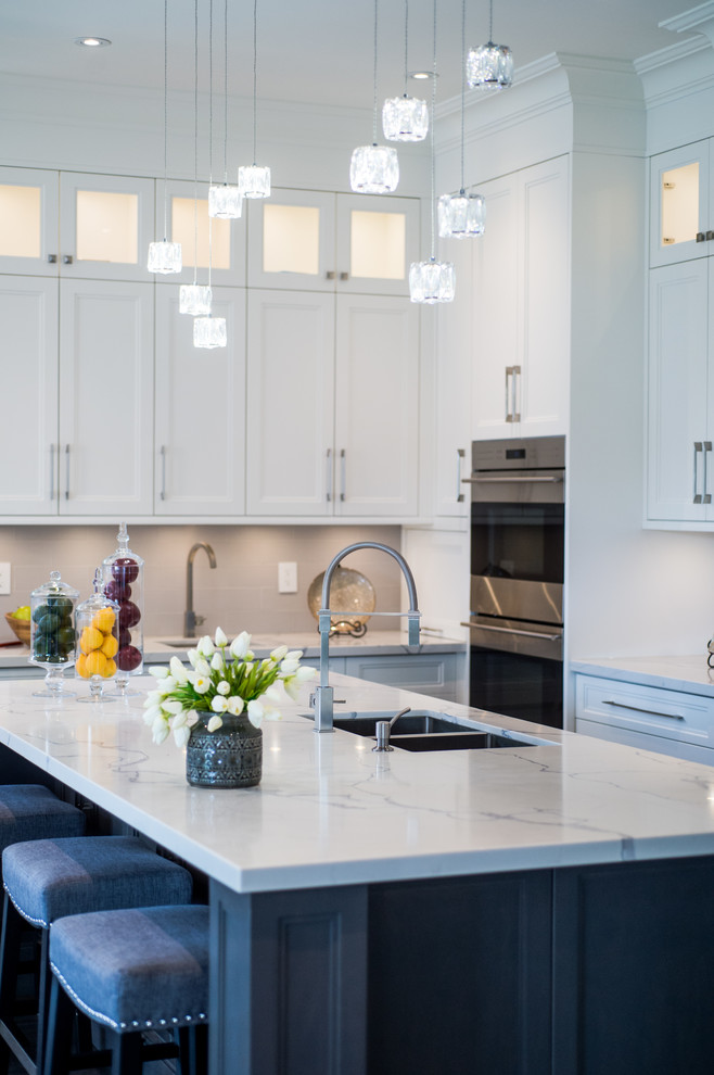 Inspiration for a large modern l-shaped kitchen/diner in Toronto with a submerged sink, marble worktops, stainless steel appliances, an island, recessed-panel cabinets, white cabinets and white worktops.