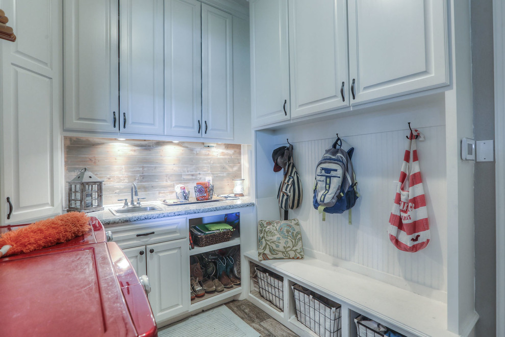 This is an example of a mid-sized country u-shaped utility room in Houston with a drop-in sink, raised-panel cabinets, white cabinets, granite benchtops, beige walls, ceramic floors, a side-by-side washer and dryer and brown floor.