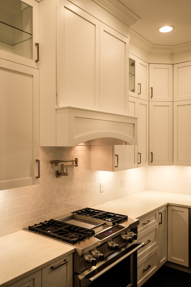 Eat-in kitchen - large transitional u-shaped dark wood floor and brown floor eat-in kitchen idea with a farmhouse sink, recessed-panel cabinets, white cabinets, quartz countertops, white backsplash, stainless steel appliances, an island and white countertops