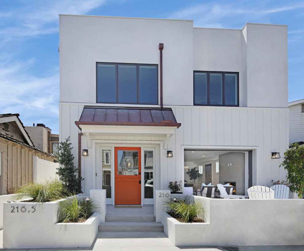 Photo of a mid-sized beach style two-storey white house exterior in Orange County with mixed siding and a flat roof.