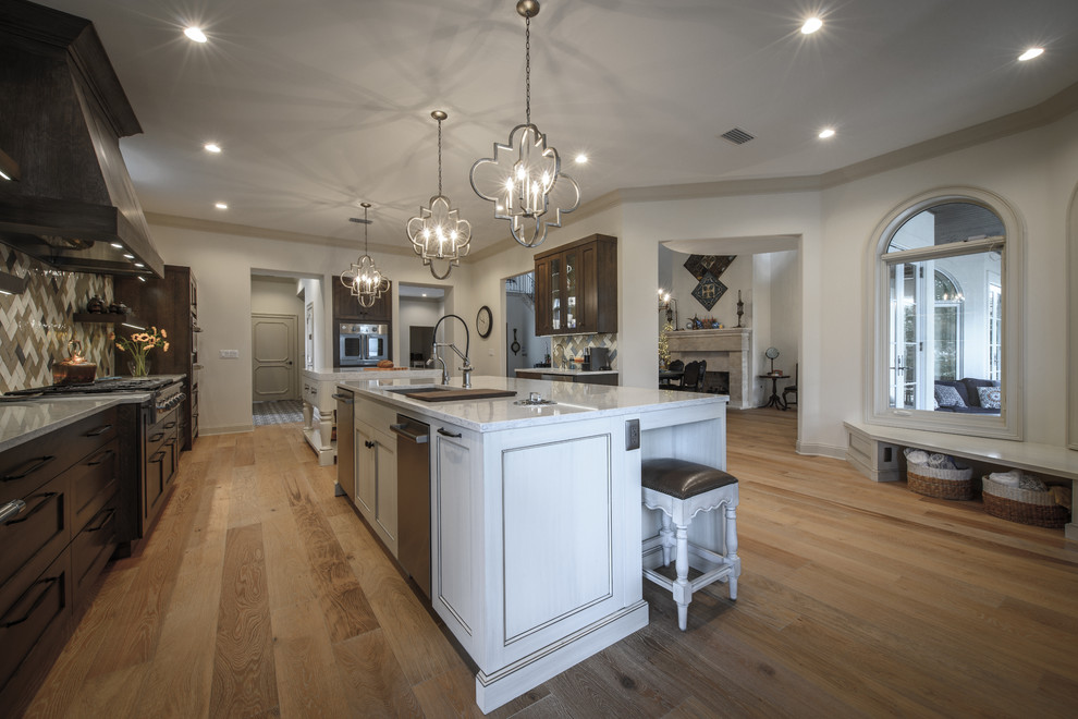 Large transitional galley light wood floor home design photo in Jacksonville with a double-bowl sink, shaker cabinets, white cabinets, quartz countertops, brown backsplash, ceramic backsplash, stainless steel appliances and two islands