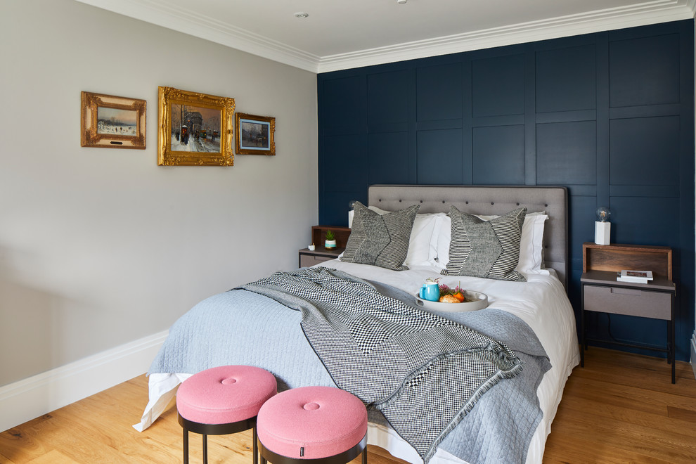 Photo of a large contemporary bedroom in Surrey with blue walls, medium hardwood floors and brown floor.