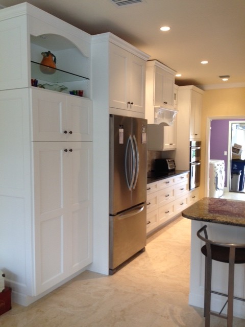 Open concept kitchen - mid-sized transitional travertine floor open concept kitchen idea with an undermount sink, shaker cabinets, white cabinets, granite countertops, beige backsplash, stone tile backsplash, stainless steel appliances and an island