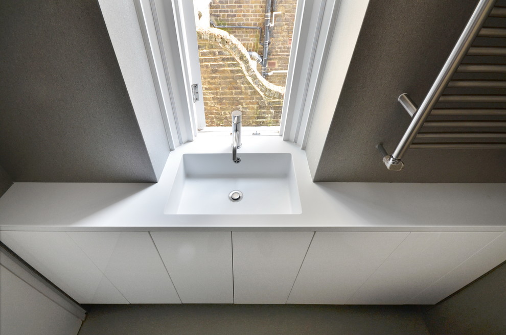 Small contemporary master wet room bathroom in London with flat-panel cabinets, white cabinets, a wall-mount toilet, gray tile, porcelain tile, grey walls, porcelain floors, a console sink, solid surface benchtops, grey floor, an open shower and white benchtops.
