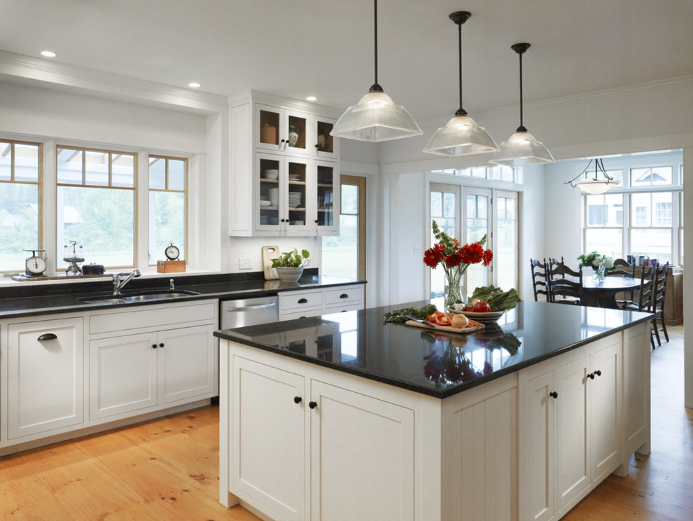 This is an example of a large country u-shaped eat-in kitchen in Burlington with black splashback, with island, an undermount sink, shaker cabinets, white cabinets, granite benchtops, stone slab splashback, stainless steel appliances and light hardwood floors.
