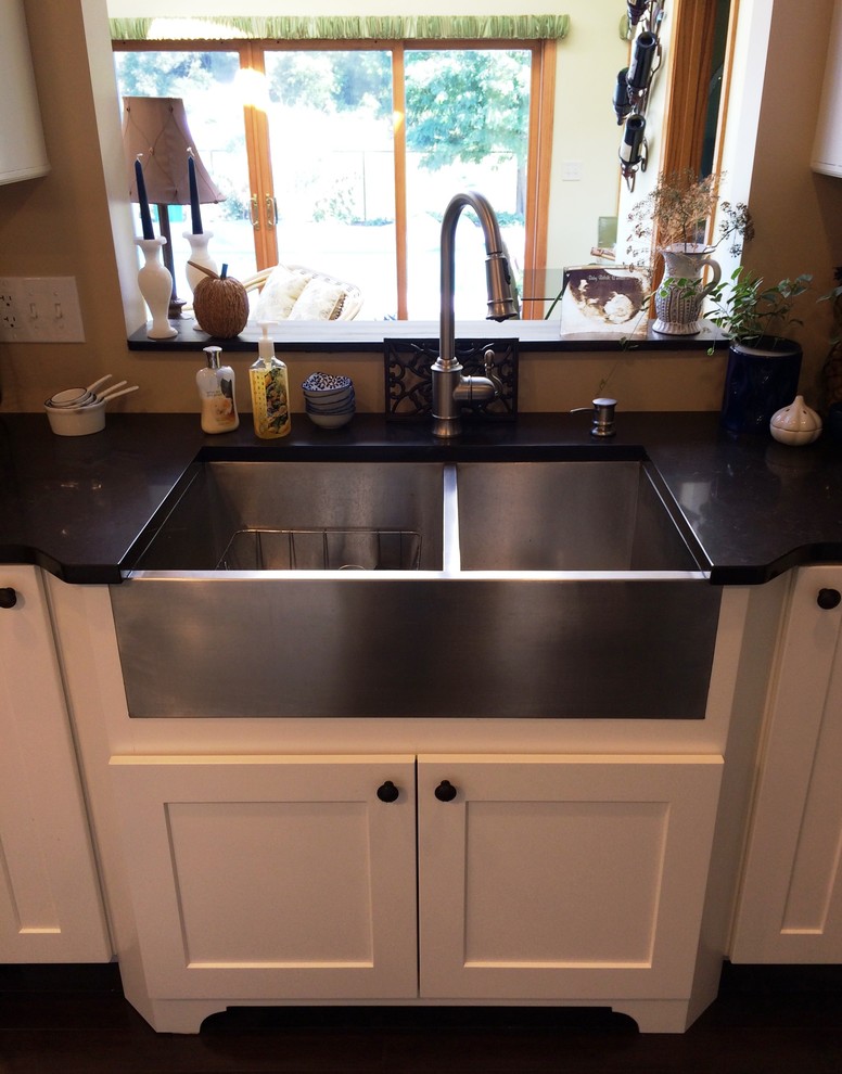 Example of a large transitional dark wood floor kitchen design in New York with a farmhouse sink, flat-panel cabinets, white cabinets, quartz countertops, stainless steel appliances and an island