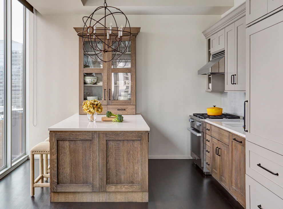 Design ideas for a transitional kitchen in Chicago with shaker cabinets, beige cabinets, white splashback, stainless steel appliances, dark hardwood floors, a peninsula and white benchtop.