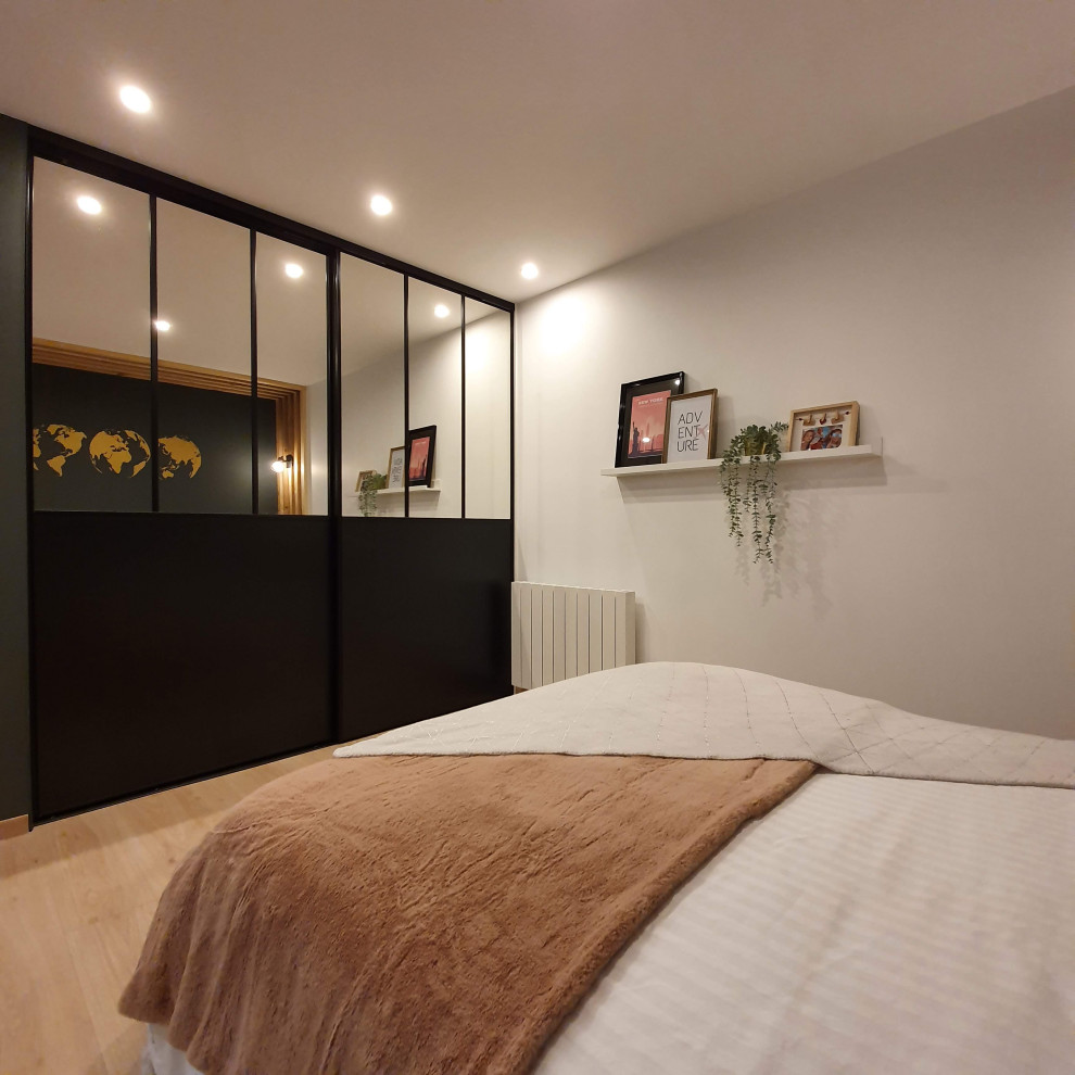 Ejemplo de dormitorio principal y blanco y madera industrial de tamaño medio con paredes negras y suelo de madera clara