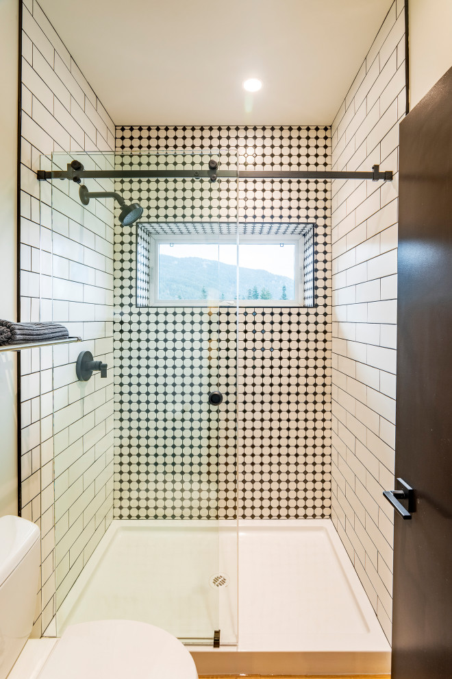 This is an example of a large modern kids bathroom in Vancouver with flat-panel cabinets, white cabinets, an open shower, a two-piece toilet, black tile, subway tile, black walls, vinyl floors, an integrated sink, brown floor, a hinged shower door and white benchtops.