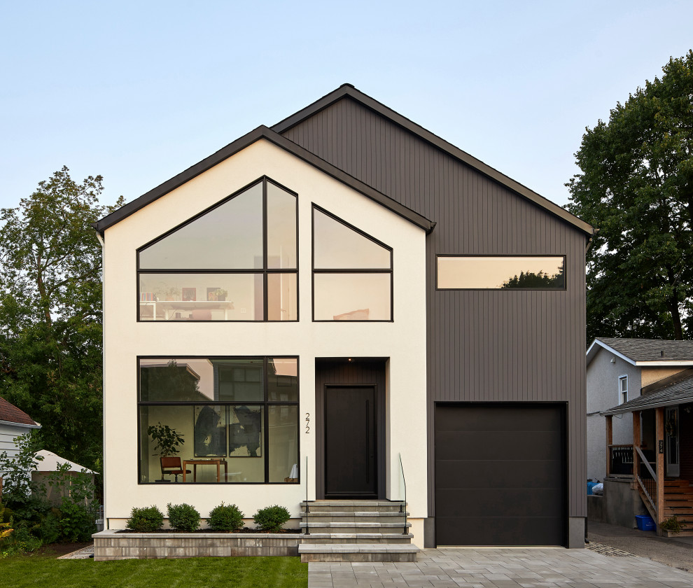 Idées déco pour une façade de maison grise scandinave en stuc à un étage avec un toit à deux pans, un toit en shingle et un toit noir.