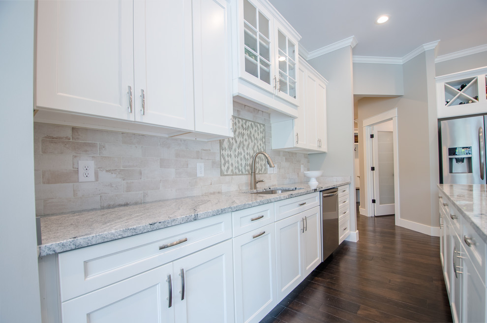 Mid-sized transitional single-wall dark wood floor eat-in kitchen photo with recessed-panel cabinets, white cabinets, granite countertops, stone tile backsplash, stainless steel appliances and an island