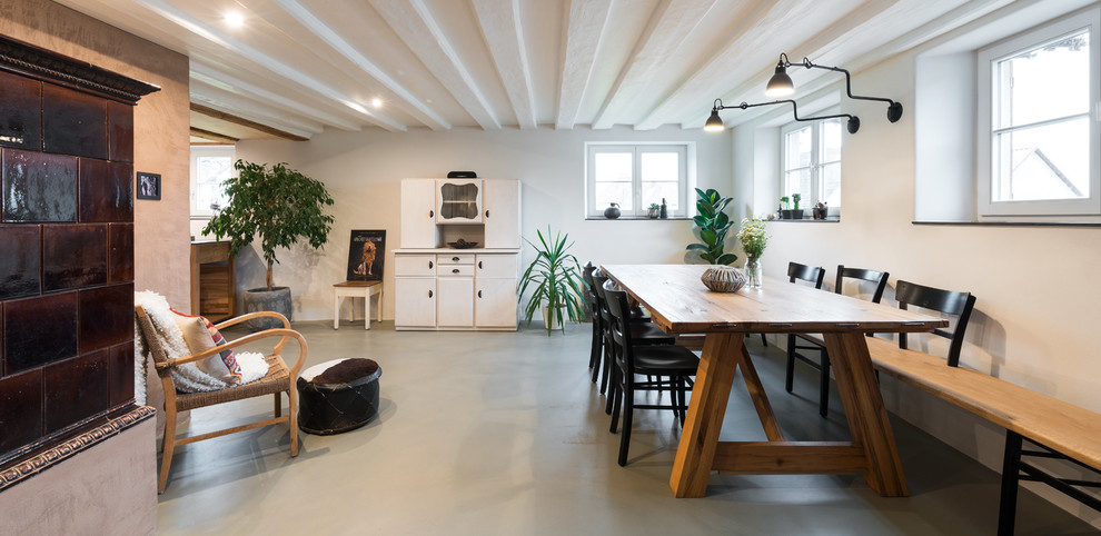 Inspiration for a large country open plan dining in Stuttgart with white walls, vinyl floors, a wood stove, a tile fireplace surround and grey floor.