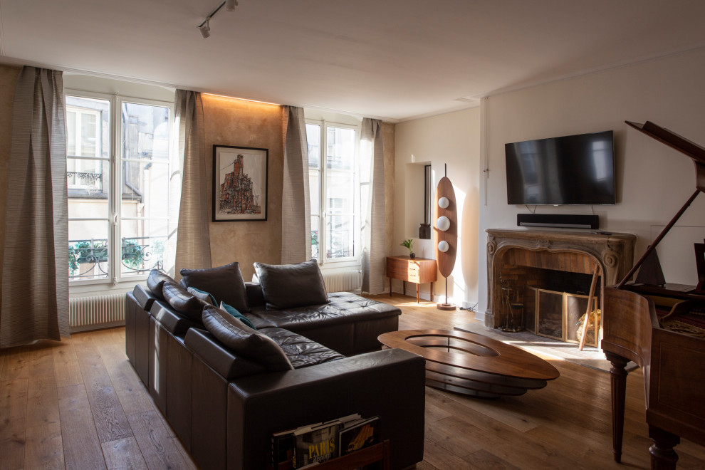 Large contemporary games room in Paris with a music area, light hardwood flooring, a stone fireplace surround, a wall mounted tv and beige floors.