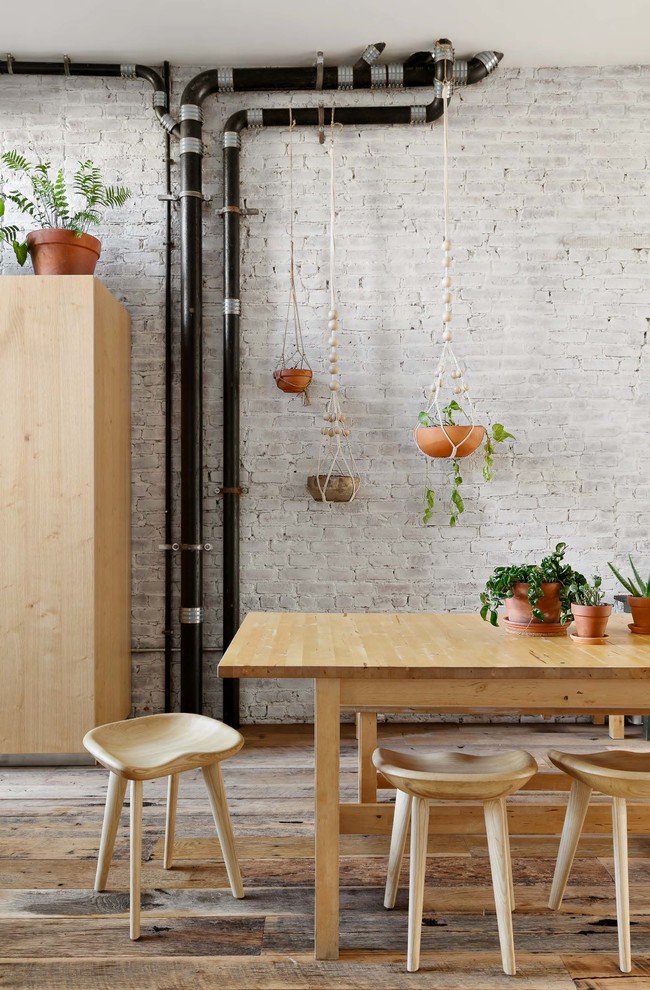Inspiration for a large industrial medium tone wood floor and brown floor kitchen/dining room combo remodel in New York with white walls, a standard fireplace and a wood fireplace surround