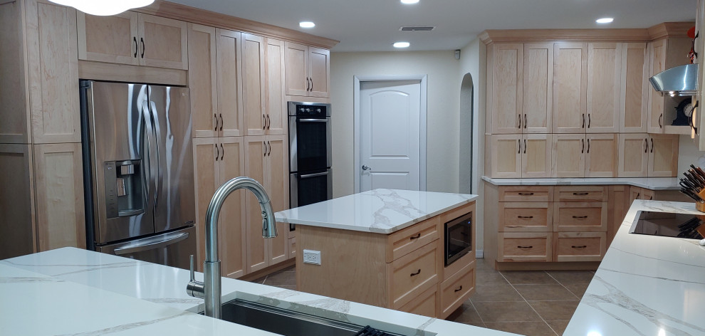 This is an example of a large tropical u-shaped open plan kitchen in Tampa with an undermount sink, shaker cabinets, light wood cabinets, quartz benchtops, multi-coloured splashback, cement tile splashback, stainless steel appliances, ceramic floors, with island, beige floor and white benchtop.