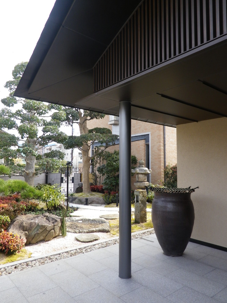 This is an example of an asian two-storey brown house exterior in Osaka with a gable roof and a metal roof.