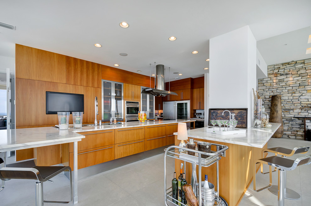 This is an example of a contemporary open plan kitchen in Miami with flat-panel cabinets, medium wood cabinets and stainless steel appliances.