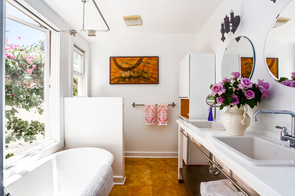 Eclectic master bathroom in Los Angeles with a drop-in sink, open cabinets, a freestanding tub, white walls, white cabinets and solid surface benchtops.
