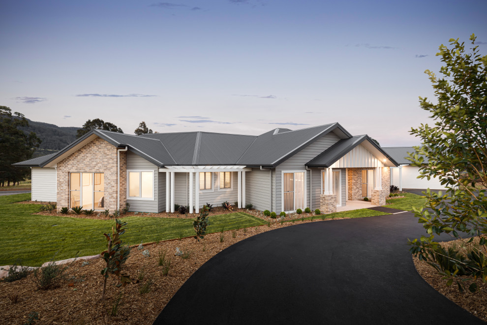 Large contemporary one-storey grey house exterior in Wollongong with a gable roof, a metal roof, a black roof and board and batten siding.