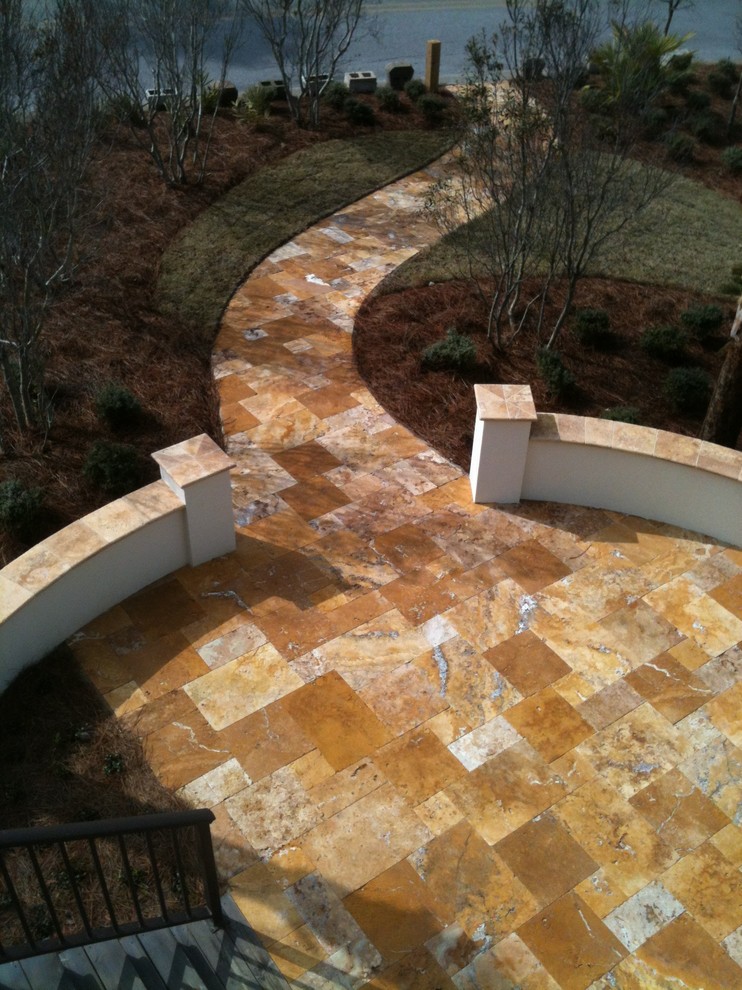 Photo of a large country backyard patio in Other with natural stone pavers and no cover.