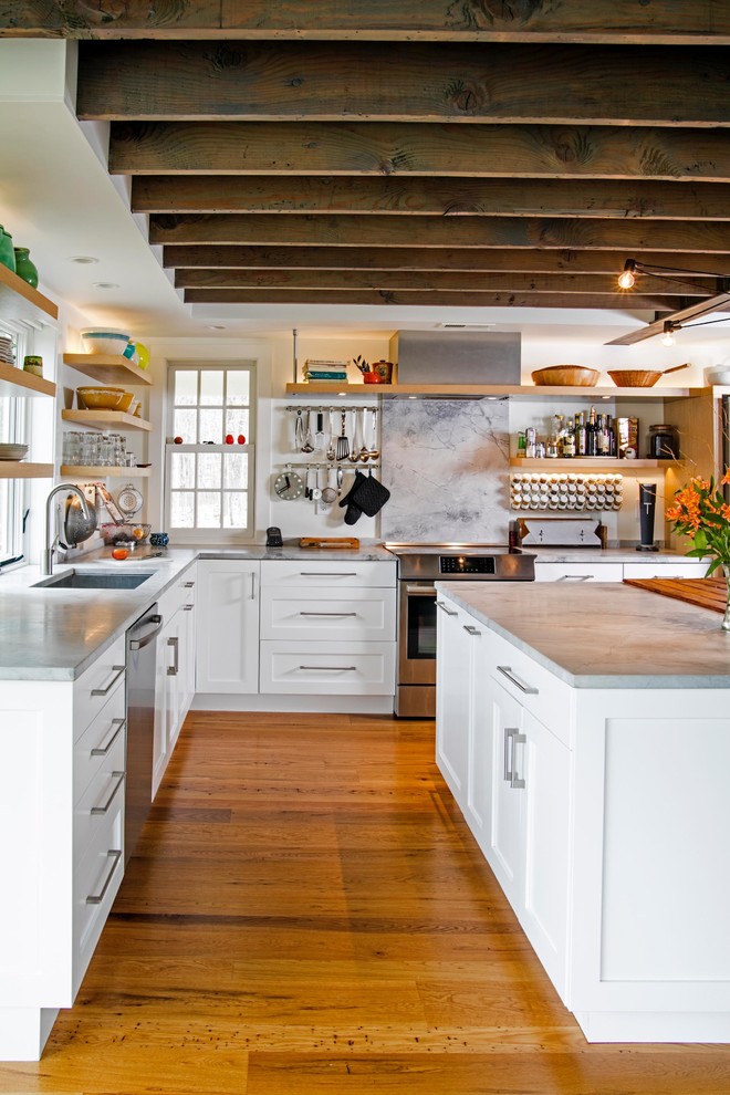 This is an example of a mid-sized eclectic l-shaped open plan kitchen in Philadelphia with a single-bowl sink, shaker cabinets, white cabinets, quartzite benchtops, stainless steel appliances, medium hardwood floors and multiple islands.