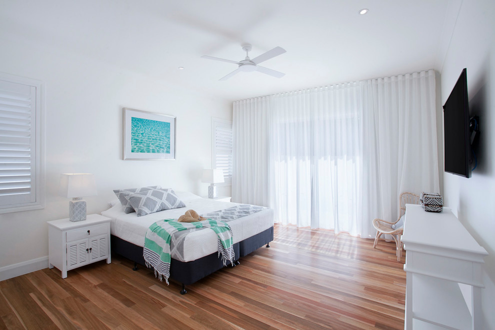 This is an example of a mid-sized beach style master bedroom in Sunshine Coast with white walls and medium hardwood floors.