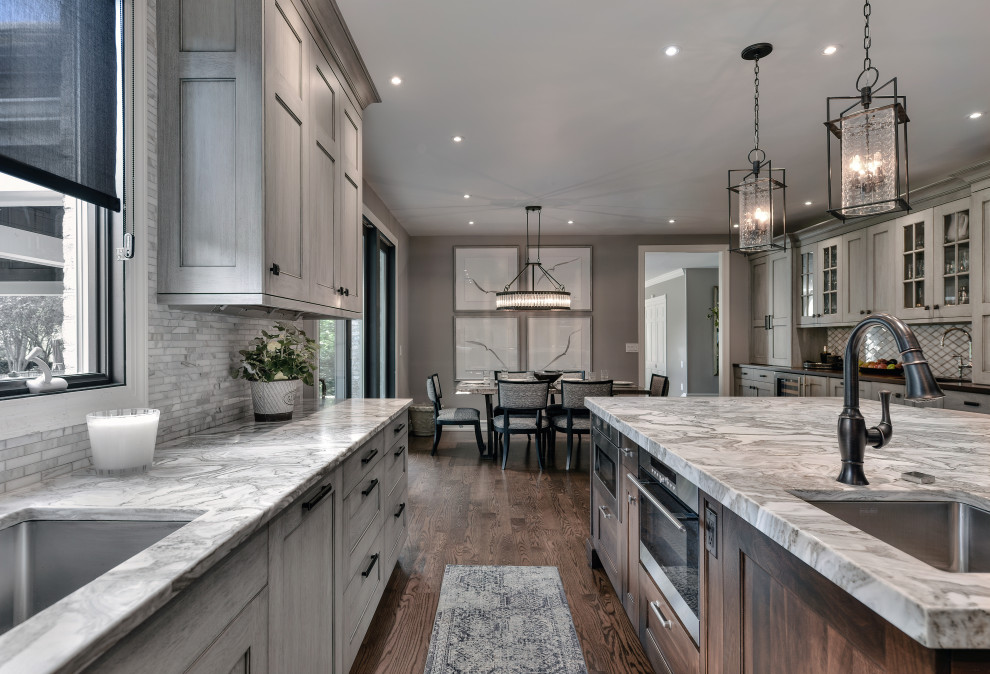 Inspiration for a large contemporary l-shaped eat-in kitchen with an integrated sink, recessed-panel cabinets, grey cabinets, quartzite benchtops, grey splashback, mosaic tile splashback, stainless steel appliances, dark hardwood floors, with island and brown floor.