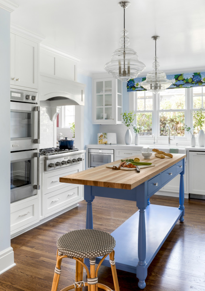 Exempel på ett mellanstort modernt kök med öppen planlösning, med en undermonterad diskho, skåp i shakerstil, vita skåp, träbänkskiva, vitt stänkskydd, rostfria vitvaror, mellanmörkt trägolv och en köksö