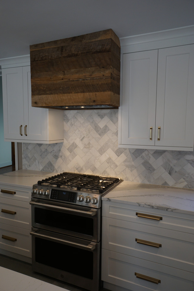 This is an example of a small country l-shaped eat-in kitchen in DC Metro with an undermount sink, recessed-panel cabinets, white cabinets, quartz benchtops, white splashback, marble splashback, stainless steel appliances, porcelain floors, with island, grey floor and white benchtop.