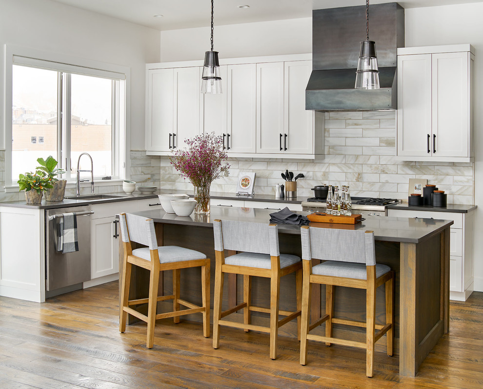 Inspiration for a transitional l-shaped kitchen in Denver with an undermount sink, shaker cabinets, white cabinets, subway tile splashback, stainless steel appliances, medium hardwood floors, with island and grey benchtop.