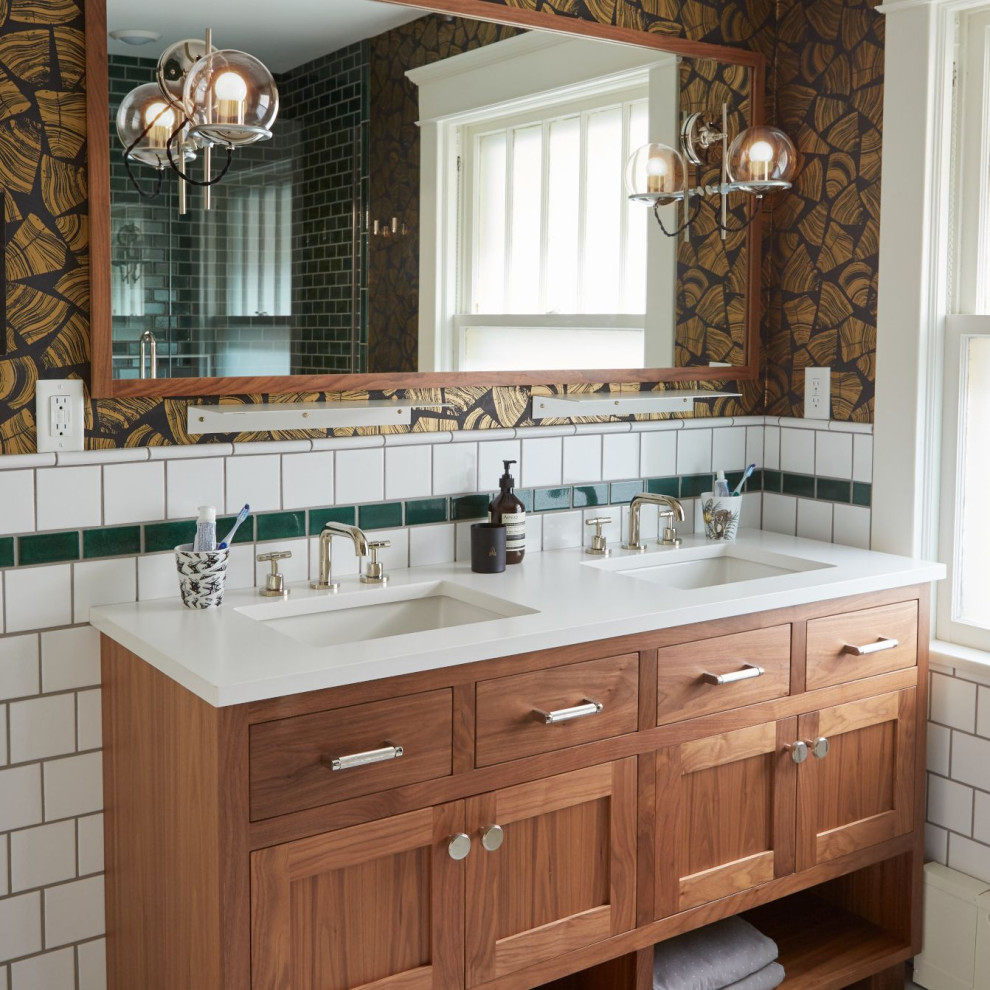 This is an example of a transitional bathroom in Minneapolis with shaker cabinets, medium wood cabinets, white tile, brown walls, an undermount sink, white benchtops, a double vanity, a freestanding vanity and wallpaper.