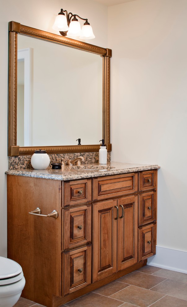This is an example of a small traditional 3/4 bathroom in New York with raised-panel cabinets, medium wood cabinets, a two-piece toilet, white walls, ceramic floors, an undermount sink, granite benchtops and beige floor.