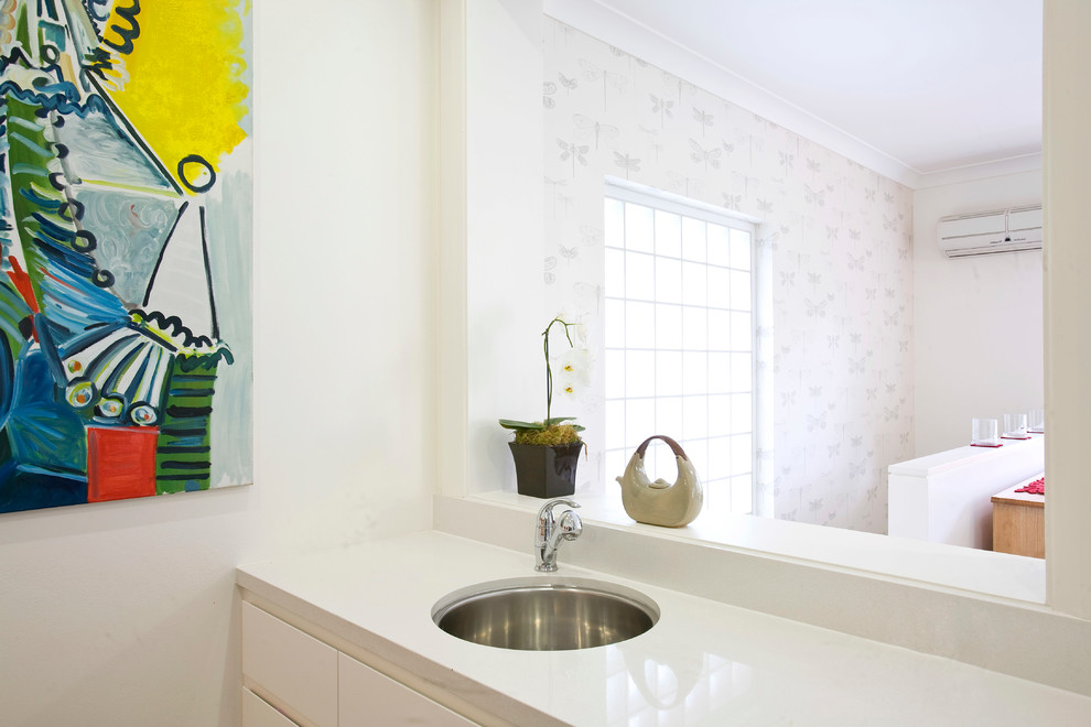 Contemporary u-shaped kitchen in Sydney with an undermount sink, flat-panel cabinets, white cabinets, quartz benchtops, glass sheet splashback and stainless steel appliances.