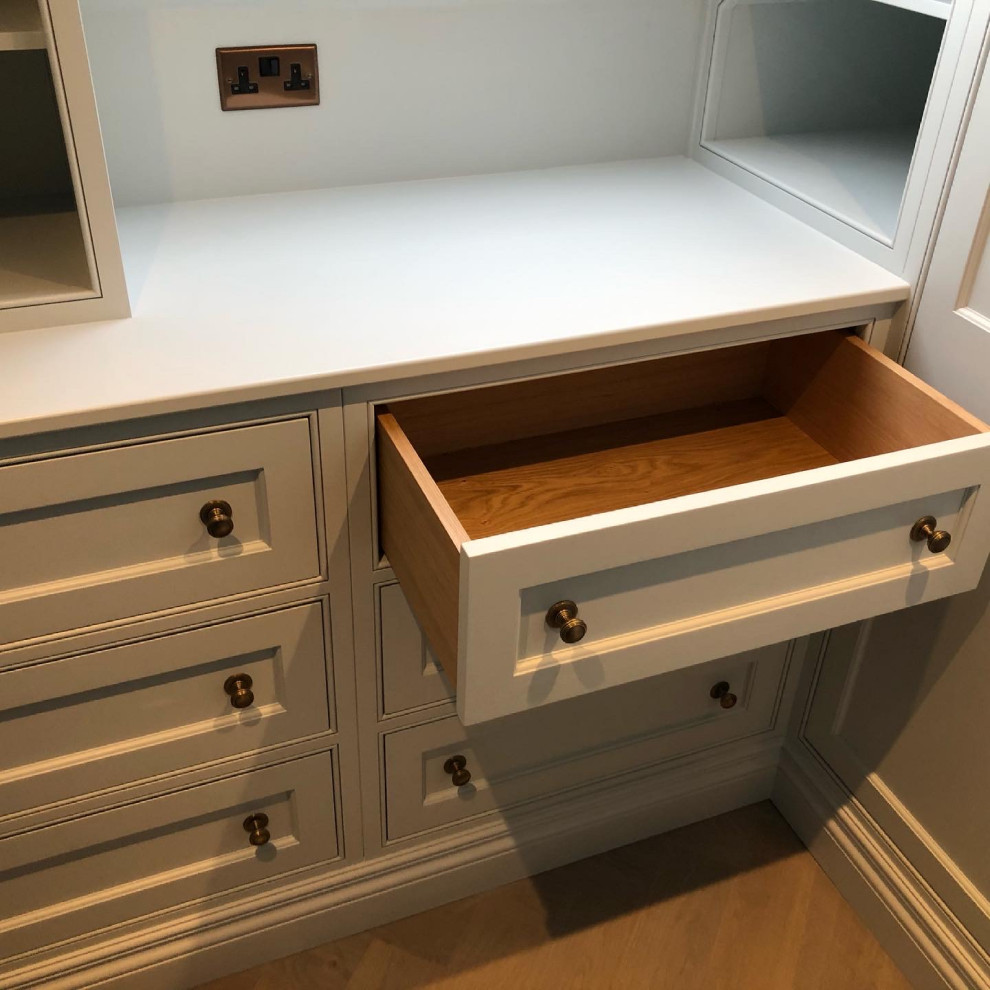 Inspiration for a small classic walk-in wardrobe for women in Sussex with recessed-panel cabinets, blue cabinets and medium hardwood flooring.