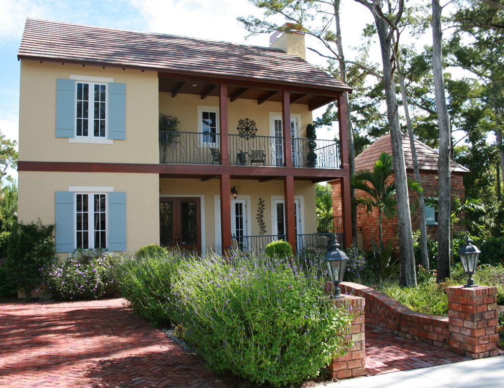 Inspiration for a large tropical two-storey stucco yellow exterior in Tampa.
