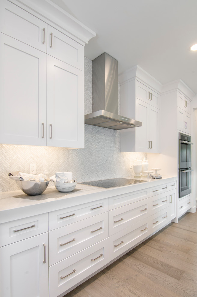 Large transitional single-wall light wood floor kitchen photo in Calgary with shaker cabinets, white cabinets, quartz countertops, white backsplash, marble backsplash, stainless steel appliances, an island and white countertops